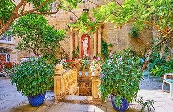 VALLETTA, MALTA - JUNE 17, 2018 - The small green garden with antique sculpture and fountain located in courtyard of historical Cassa Rocca Picola palace, on June 17 in Valletta.